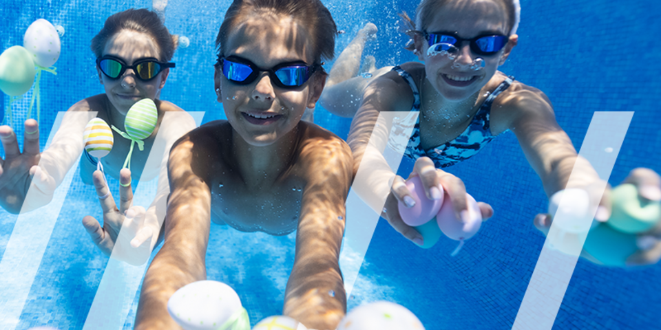 Drie kinderen zwemmen onder water met paaseitjes in hun handen
